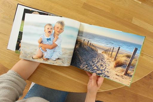 Twee bladzijden uit een fotoboek met foto's van kinderen en het strand voor de zee