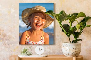 Meisje met hoed bij de zee op canvas op een zandkleurige muur
